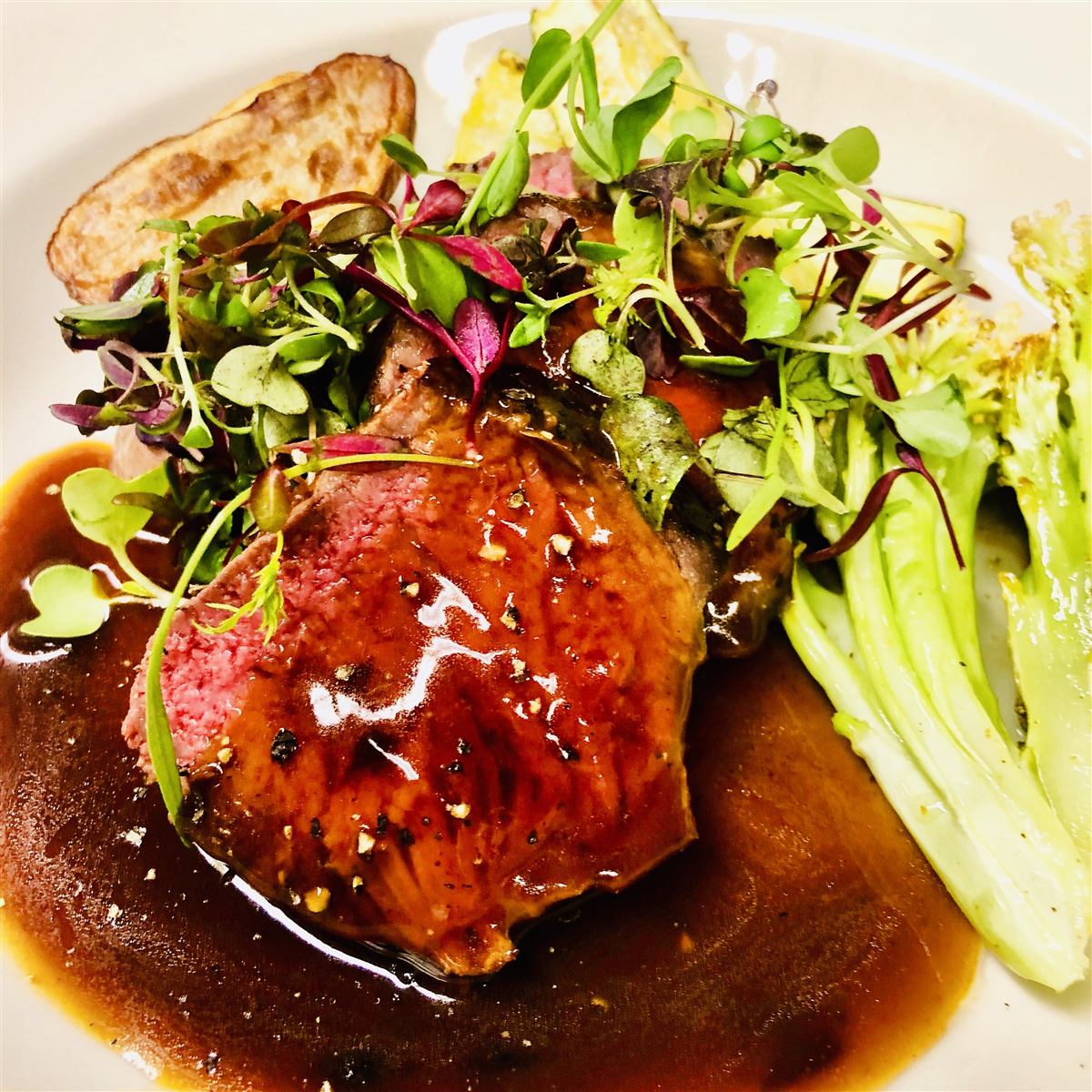 Medium-rare beef tenderloin with microgreens and demi-glace