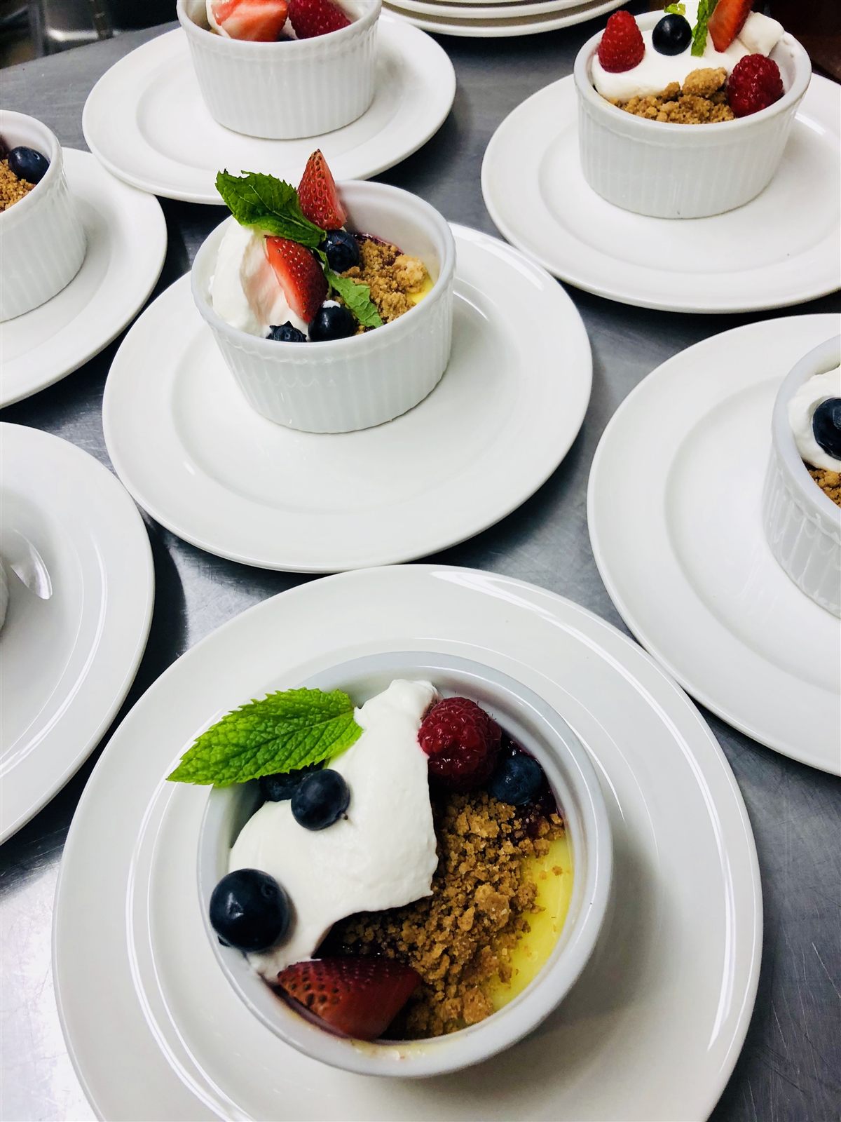 Mixed berry dessert ramekins with whipped cream and mint — private dinner service
