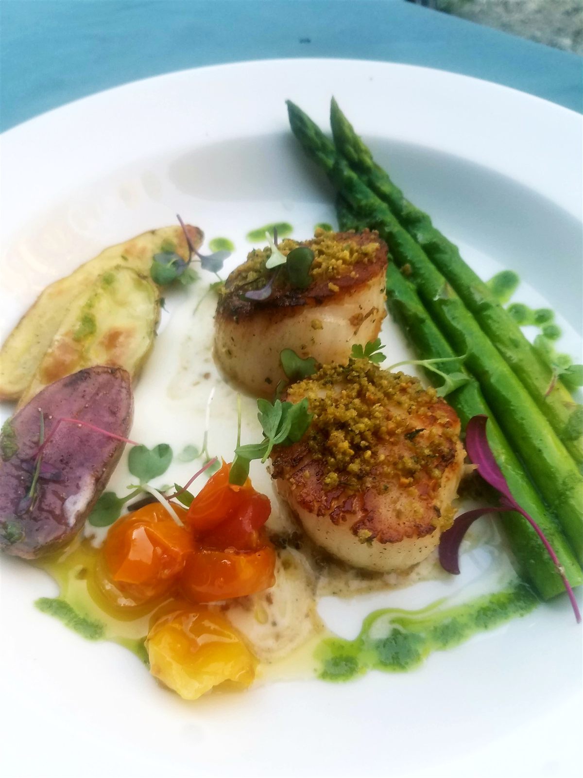 Pan-seared scallops with asparagus, heirloom tomatoes, and pesto drizzle