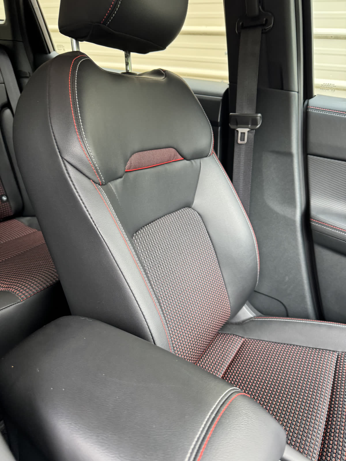 Kicks SR driver seat — red-stitch sport upholstery