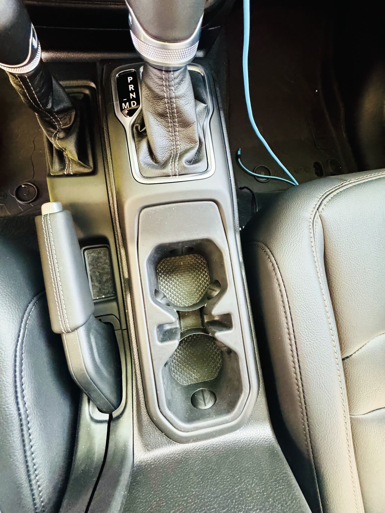 2025 Jeep Wrangler Sahara center console with automatic shifter, cupholders and premium leather seating