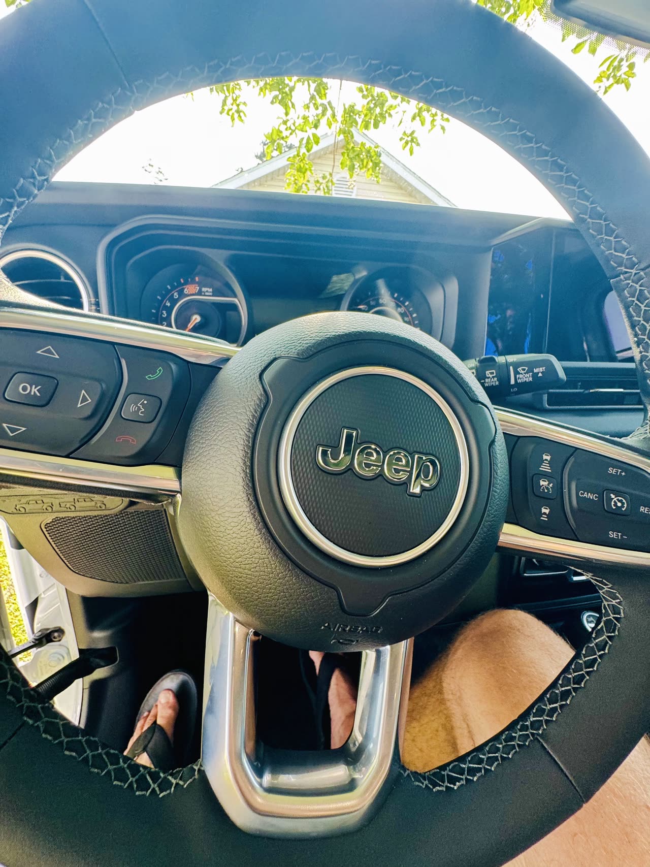 2025 Jeep Wrangler Sahara steering wheel with Jeep badge and saddle-brown leather interior, Apple CarPlay-ready cockpit
