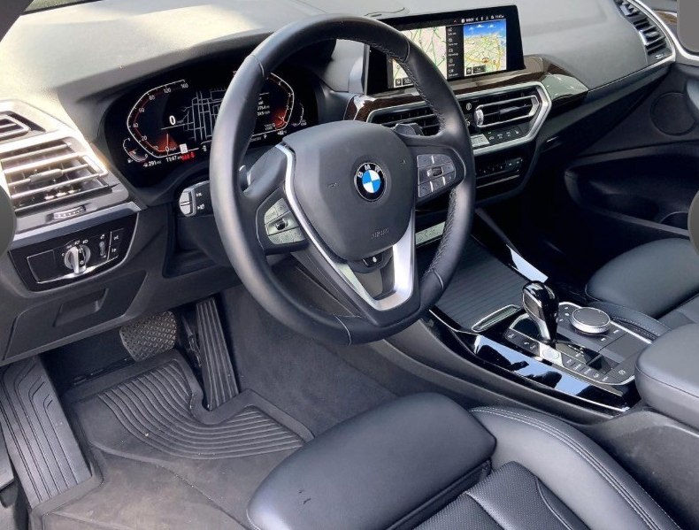 BMW X3 front interior — steering wheel, BMW badge, and console